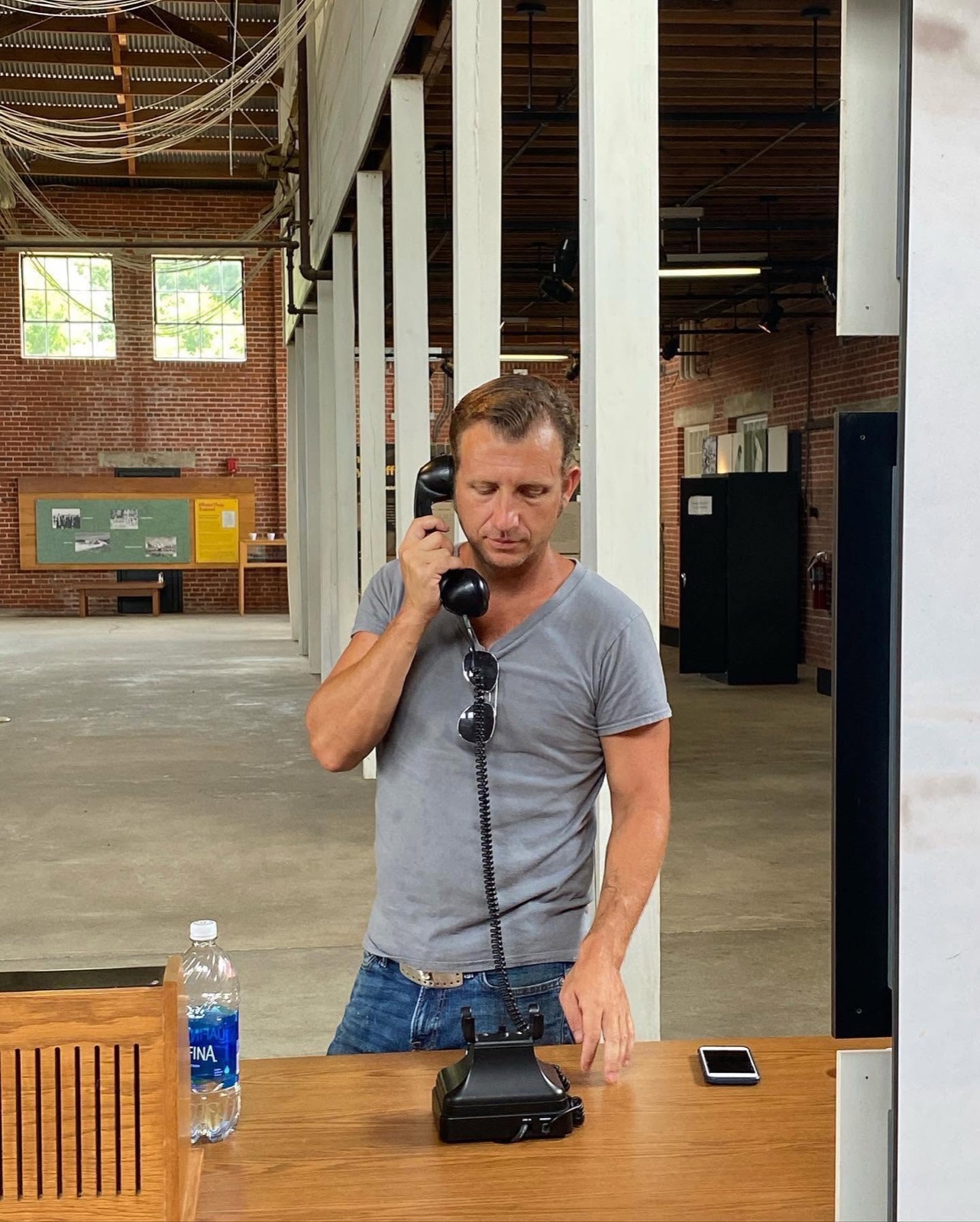Mike Shaner on a telephone in an empty brick-and-timber hall.